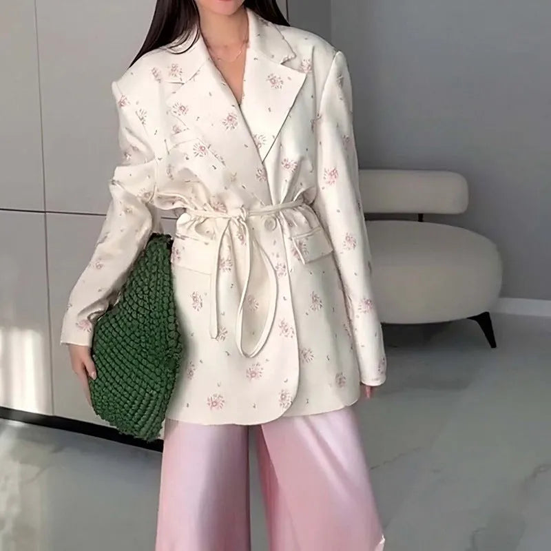 Women's white blazer with a lace-up fastening detail at the waist, shown on a hanger.
