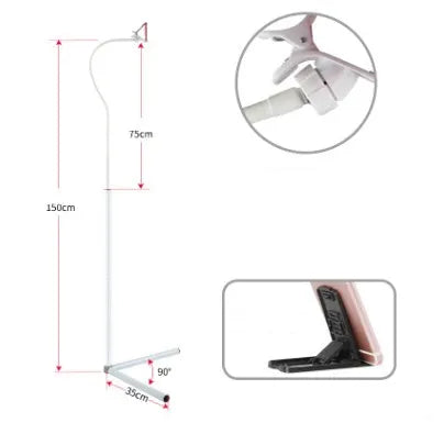 A black mobile phone bed bracket clipped to a bed frame, holding a smartphone in an overhead viewing position.