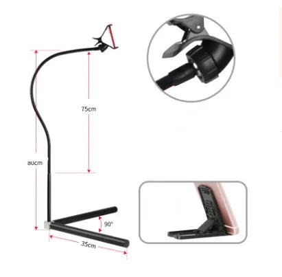 A black mobile phone bed bracket clipped to a bed frame, holding a smartphone in an overhead viewing position.
