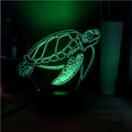 Clear acrylic 3D turtle-shaped LED night light showing multiple colour options on a dark surface.
