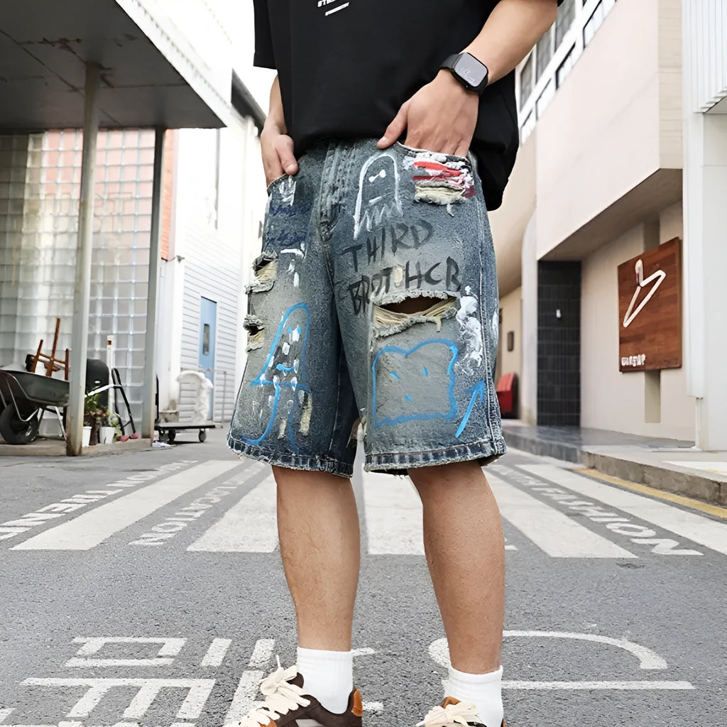 Blue ripped denim jeans shorts for men with graffiti design and straight leg opening.