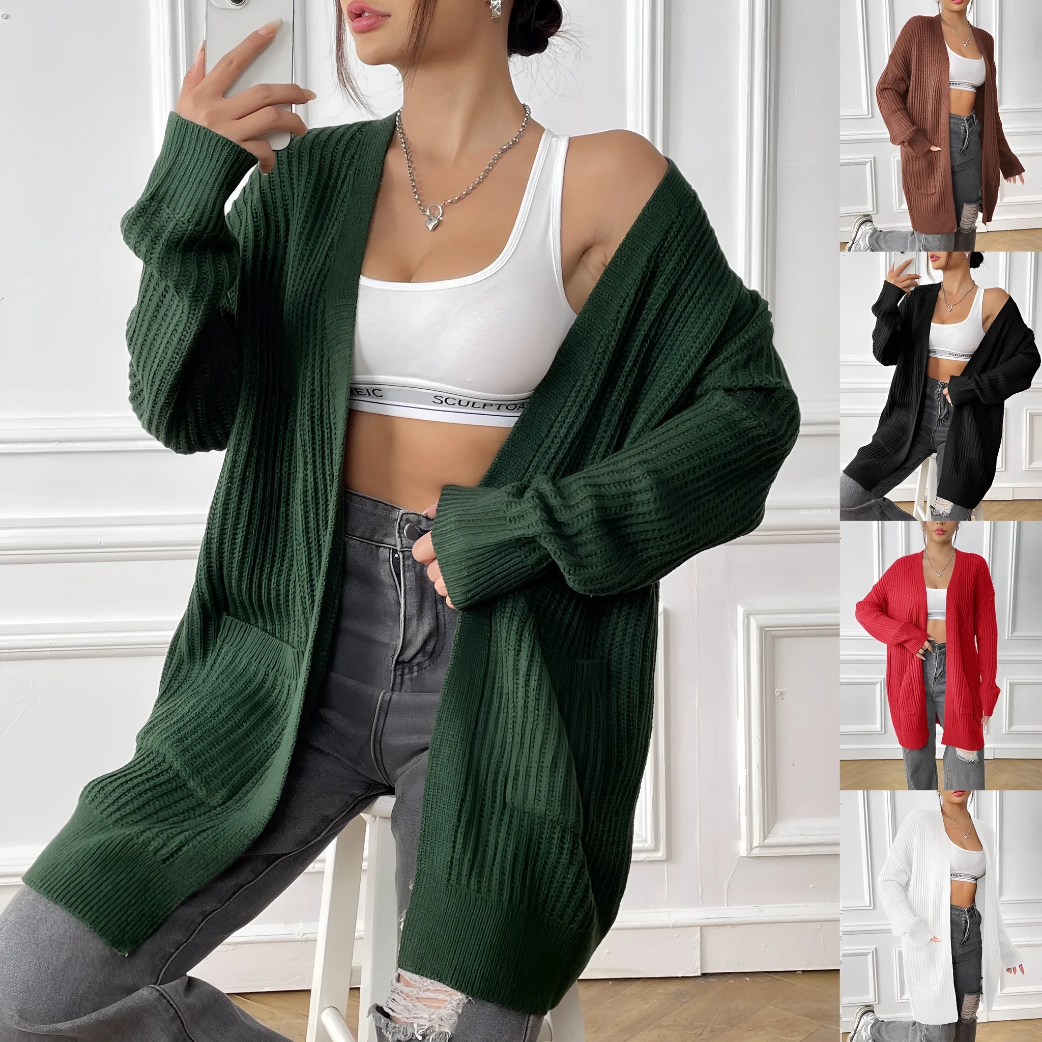 A woman wearing a loose-fitting, mid-length dark green cardigan sweater with double pockets.