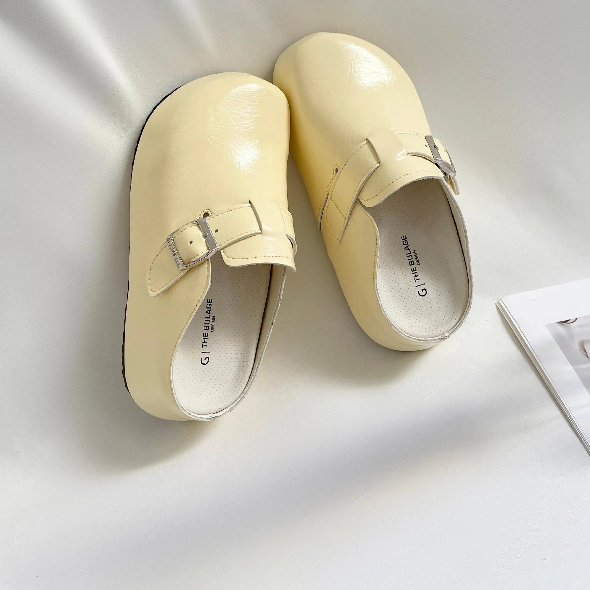 Flat buckle casual sneakers in yellow, black, silver, and creamy-white on a white background.