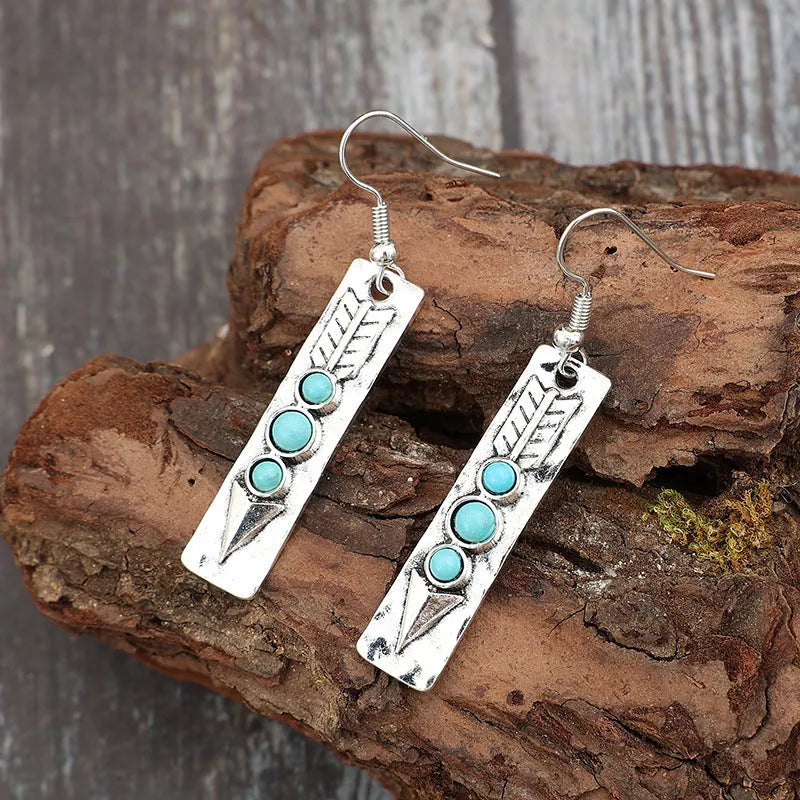 Silver geometric drop earrings with turquoise inlay details on white background