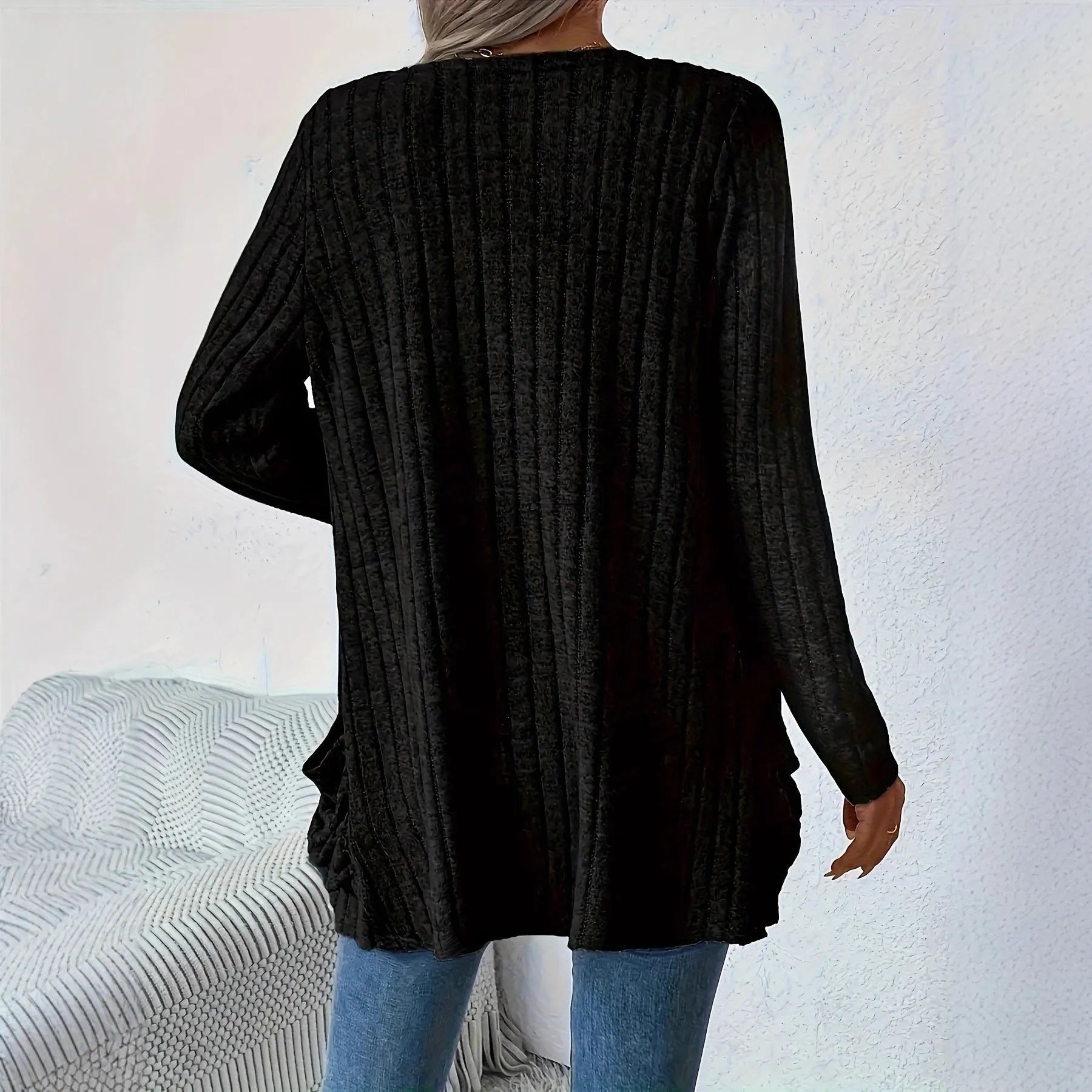 A grey loose fit long sleeve cardigan with pockets hanging on a hanger.