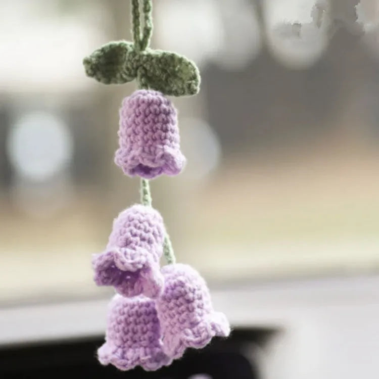 Green and white knitted wool car plant decoration with white hanging rope.