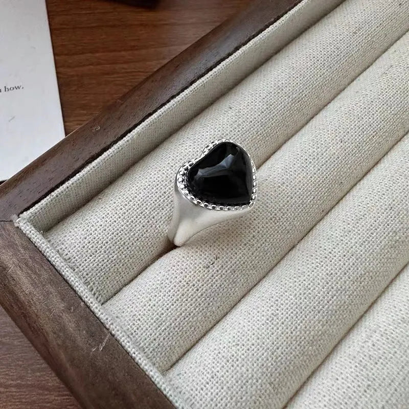 S925 sterling silver adjustable ring with a black agate heart centrepiece on a finger.