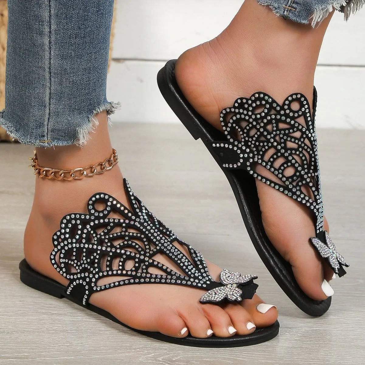 Women's black slip-on sandals with rhinestone flip-toe design and hollow detailing on the upper.