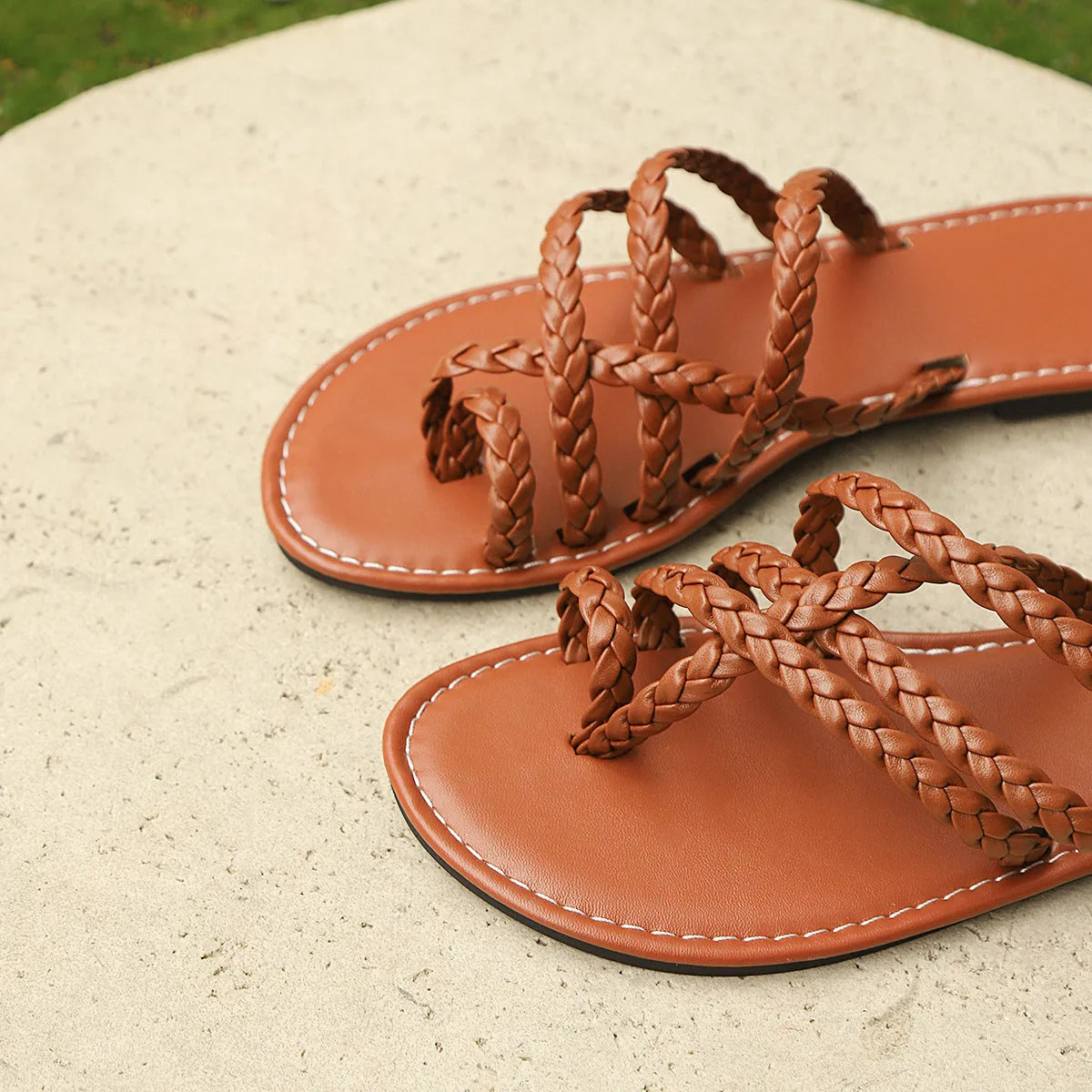 Women's woven artificial PU clip-toe Roman sandals with a flat rubber sole, shown in black.