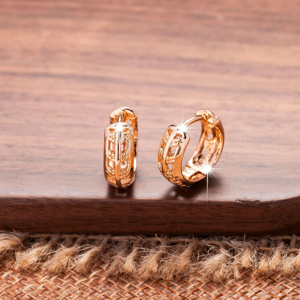 Small copper earrings with a hollowed-out heart-shaped leaf design in rose gold finish.