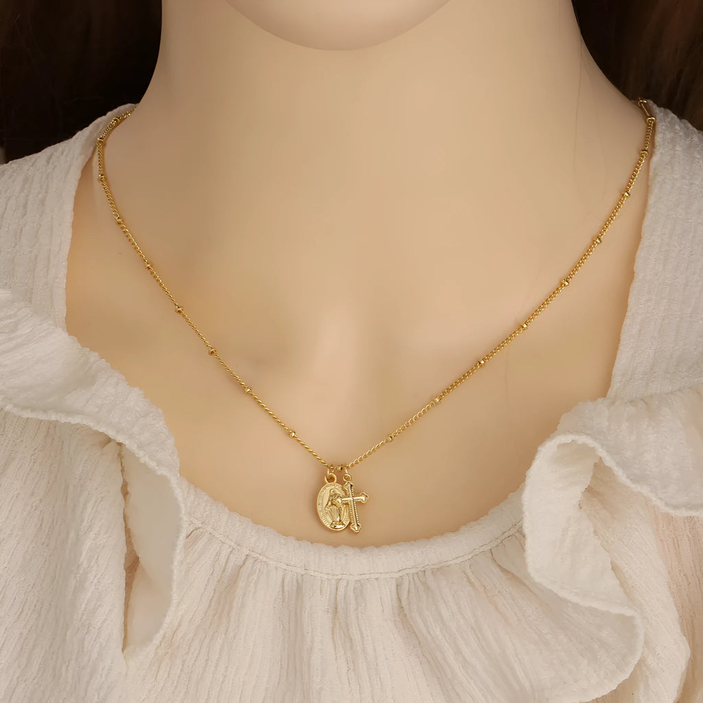 Gold geometric cross and Virgin Mary pendant necklace on display