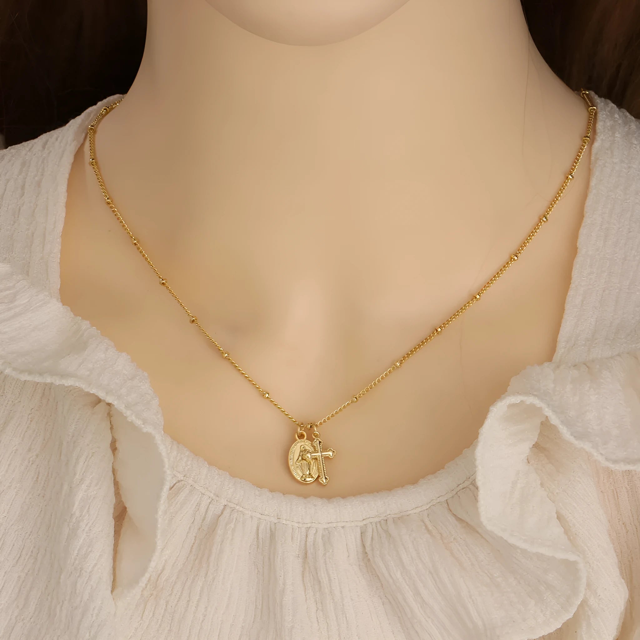 Gold geometric cross and Virgin Mary pendant necklace on display