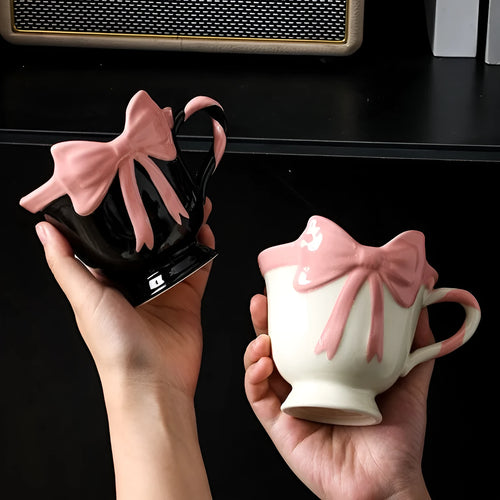 Ceramic mug with a pink and white girl's heart bow decoration on the side.
