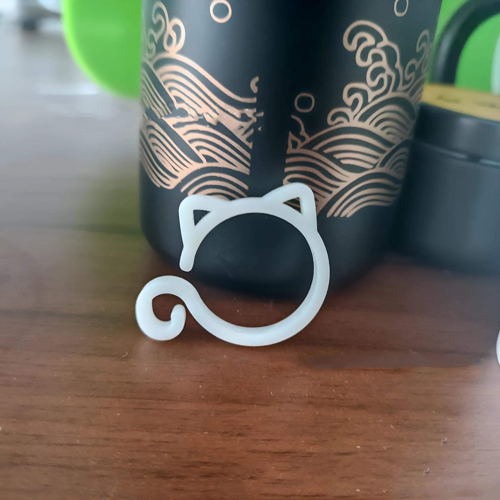 Red cat-shaped plastic gardening clip for plant support on green leaves