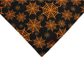 Black and orange reversible Halloween dog bandana with pumpkin and spider web patterns showing adjustable closure