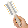 White double-sided dog and cat brush with curved comb and deshedding bristles on an ergonomic handle.