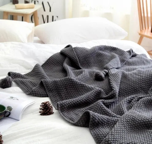 Nordic fringed knit ball acrylic blanket in beige colour on a sofa