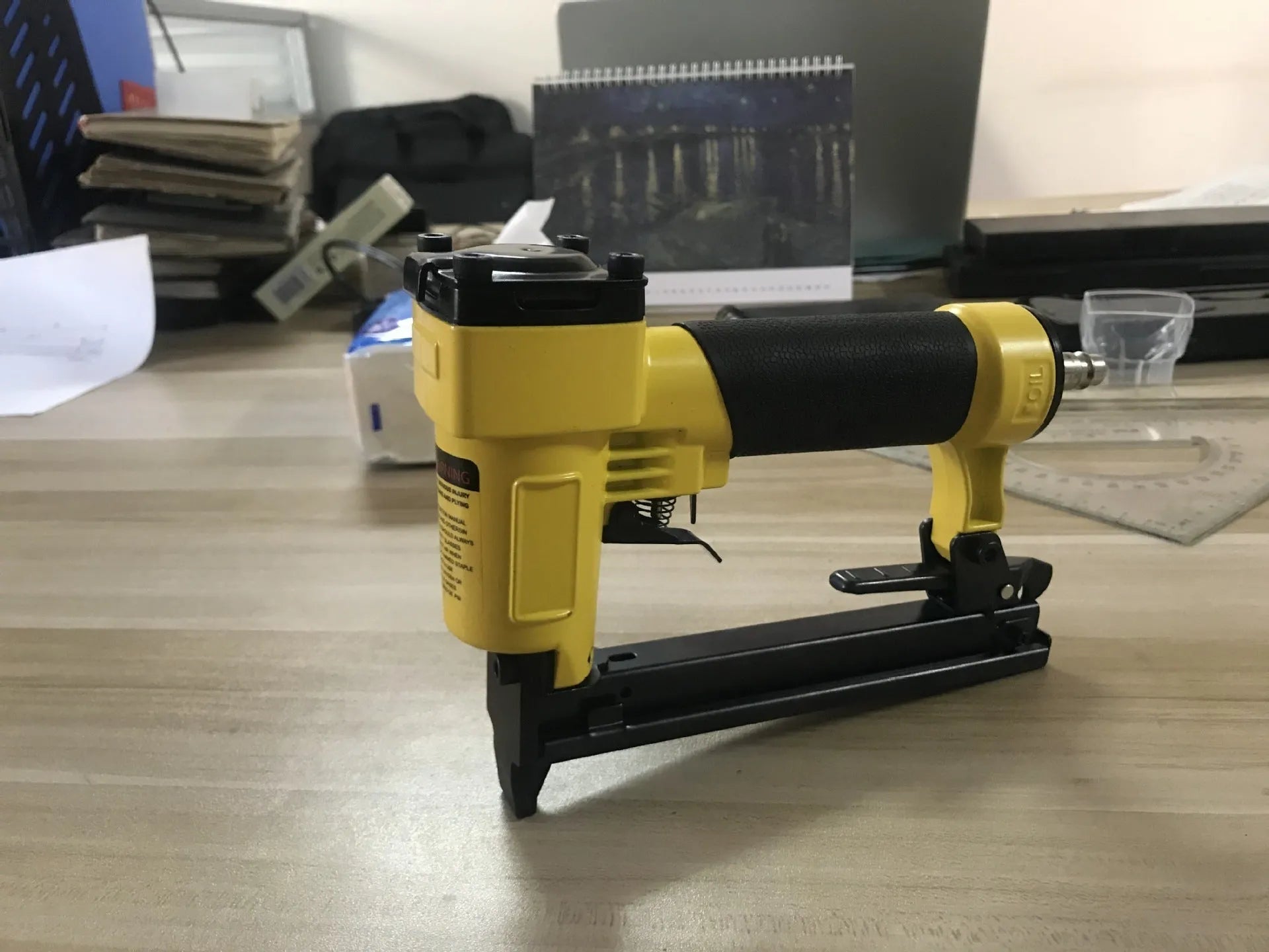 Blue and yellow U-type pneumatic strip nail gun with American connector for furniture and interior work.