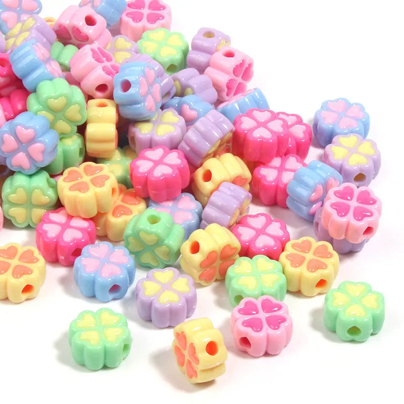 A pile of 15mm frosted acrylic four-leaf clover beads in mixed colours including pink, green, and blue.