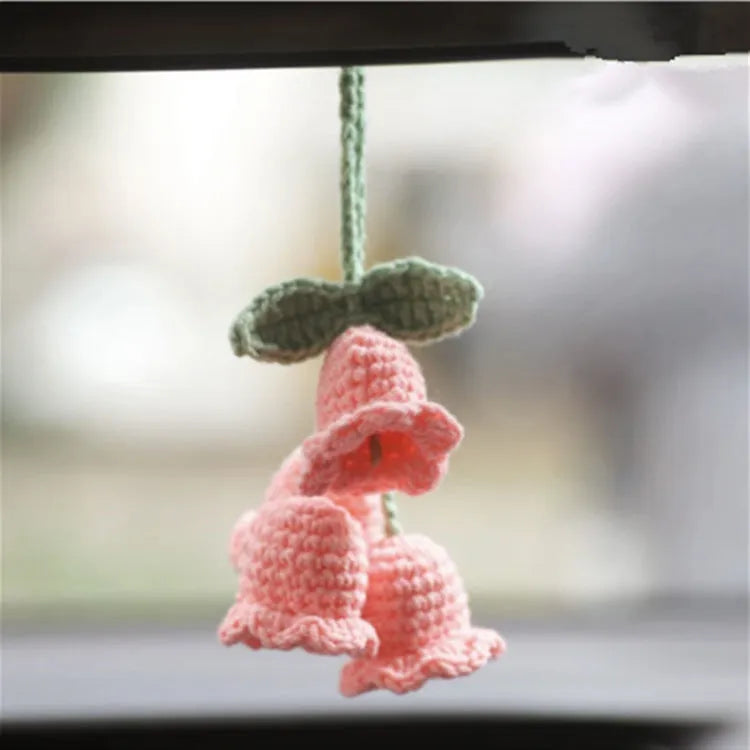 Green and white knitted wool car plant decoration with white hanging rope.