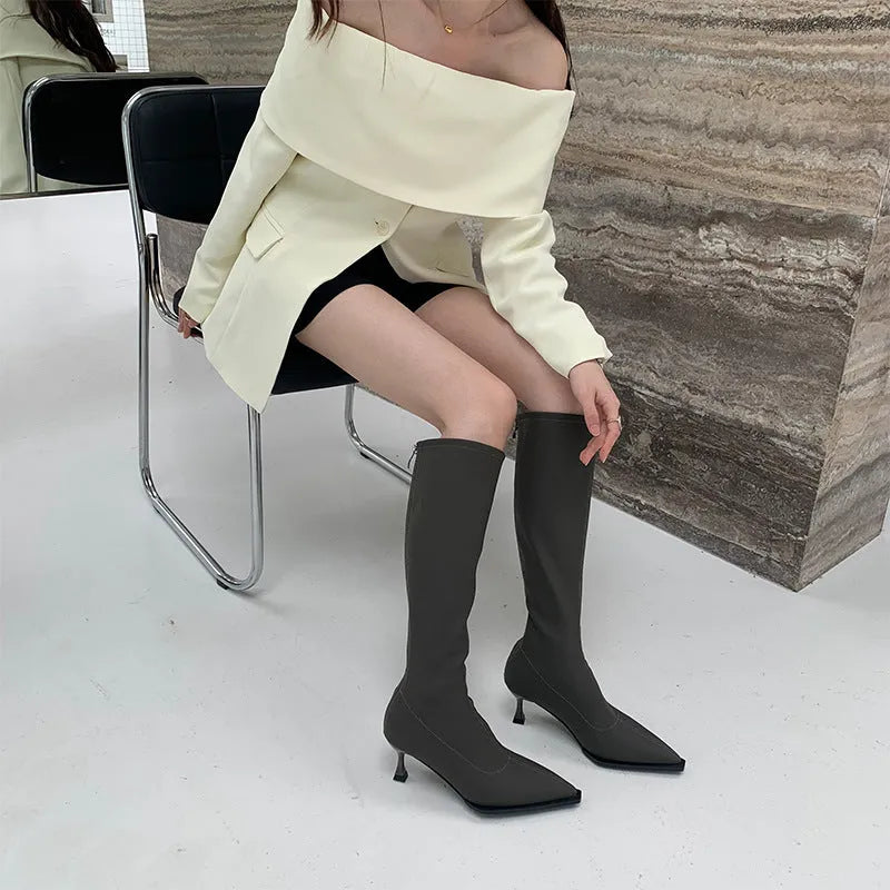 Black women's pointed toe stiletto heel boots with a back zipper, shown below the knee.