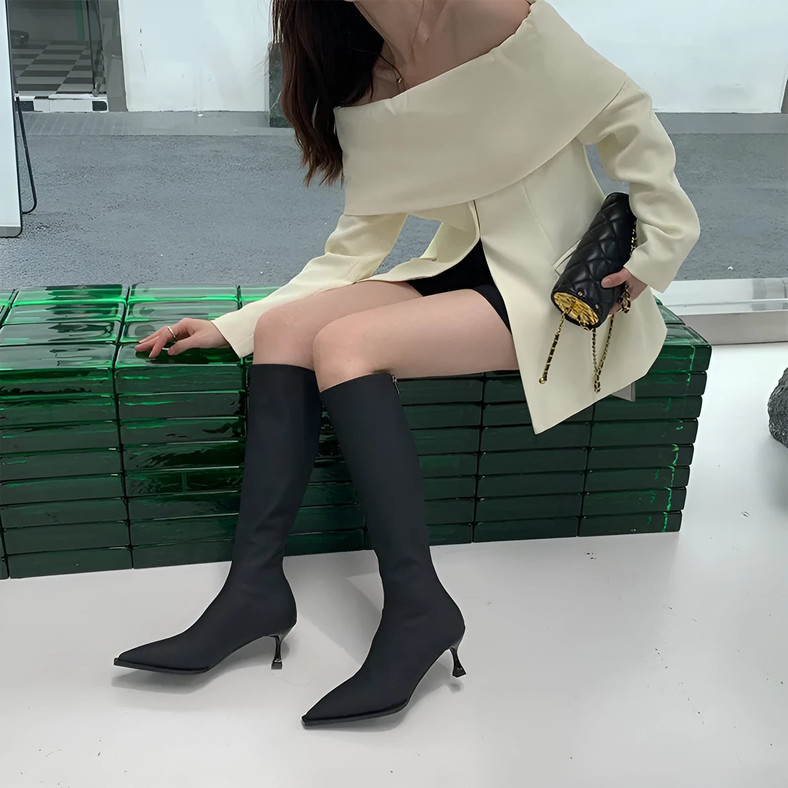 Black women's pointed toe stiletto heel boots with a back zipper, shown below the knee.