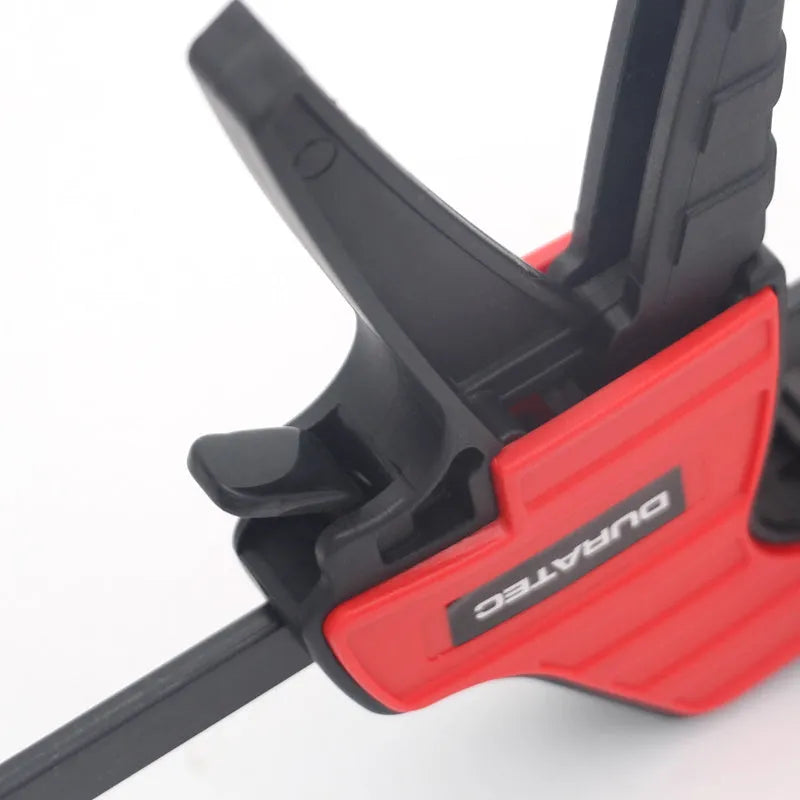 Black plastic woodworking clamp with quick-adjust key and soft rubber protective jaws.