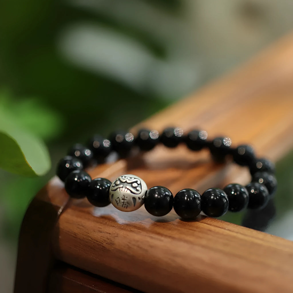 Close-up of a women's bracelet with large black agate beads and sterling silver, showing Chinese style design.