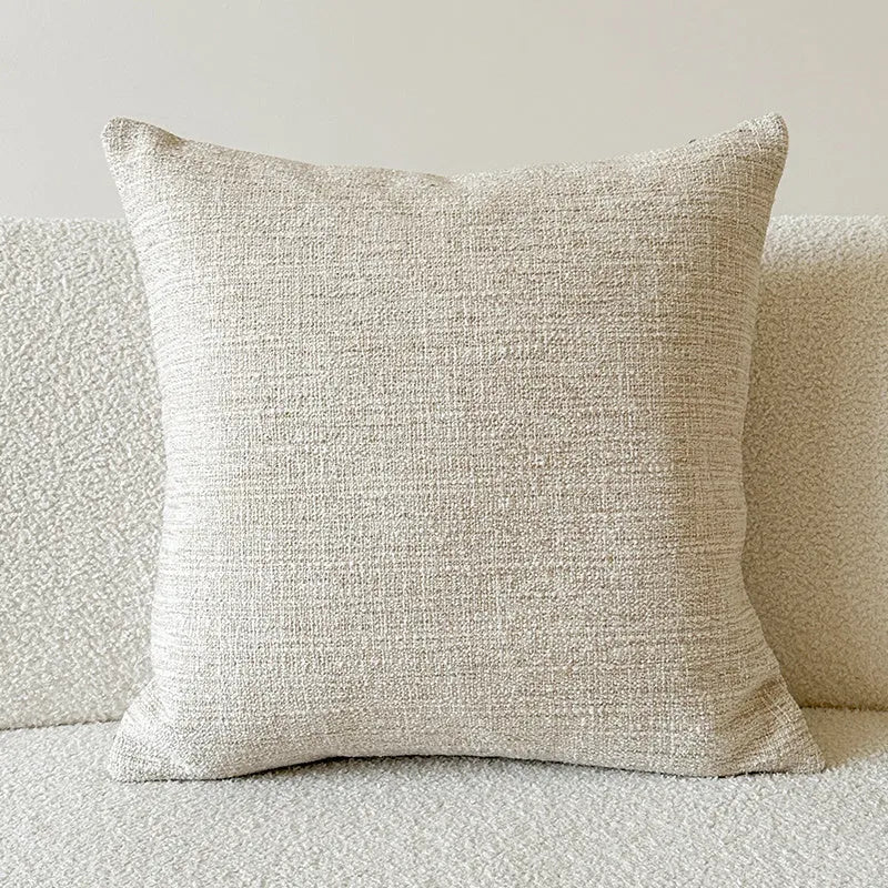 Amber coloured jacquard pillow cover with paisley and floral pattern, shown on a sofa.