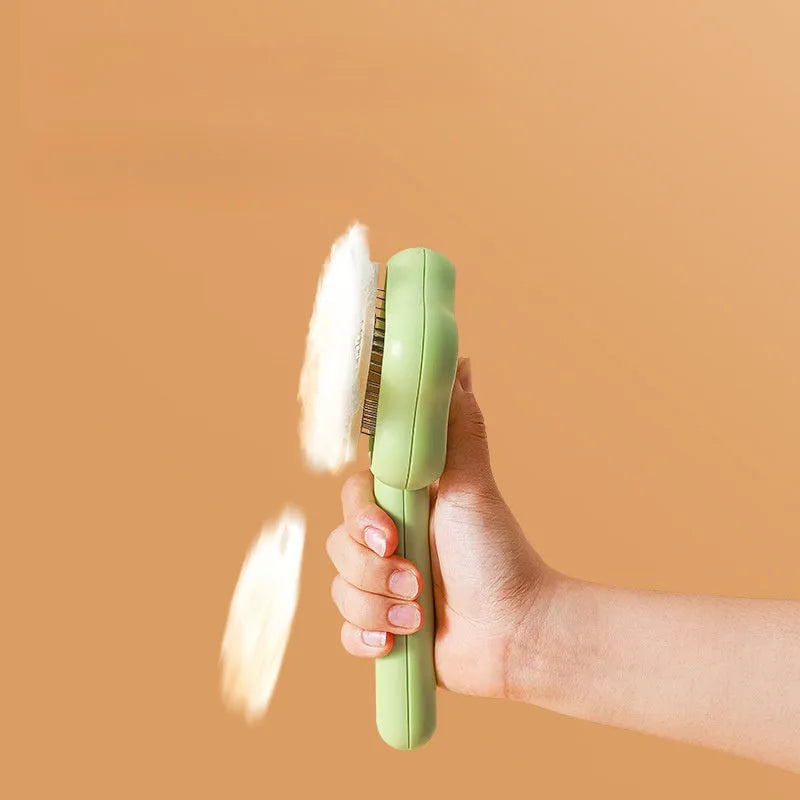 Green stainless steel self-cleaning cat comb with needle bristles on a white background.