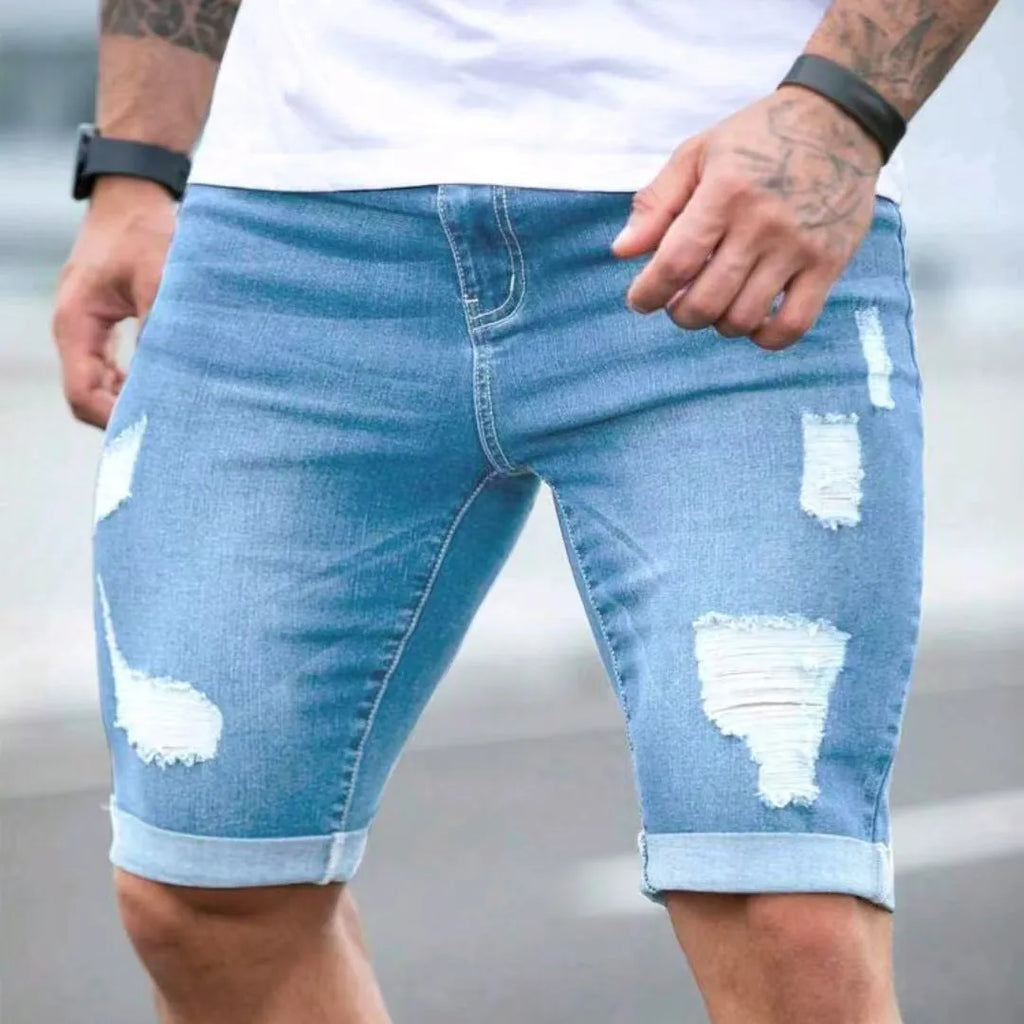 Sky blue denim shorts with multiple distressed holes and straight leg silhouette