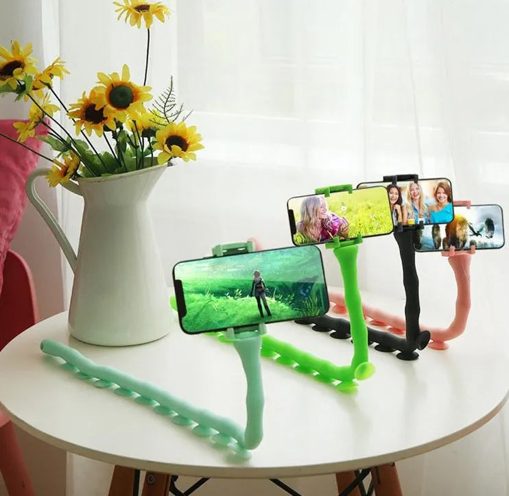 Flexible rubber phone holder with suction cup mounted on desktop showing 360-degree rotation