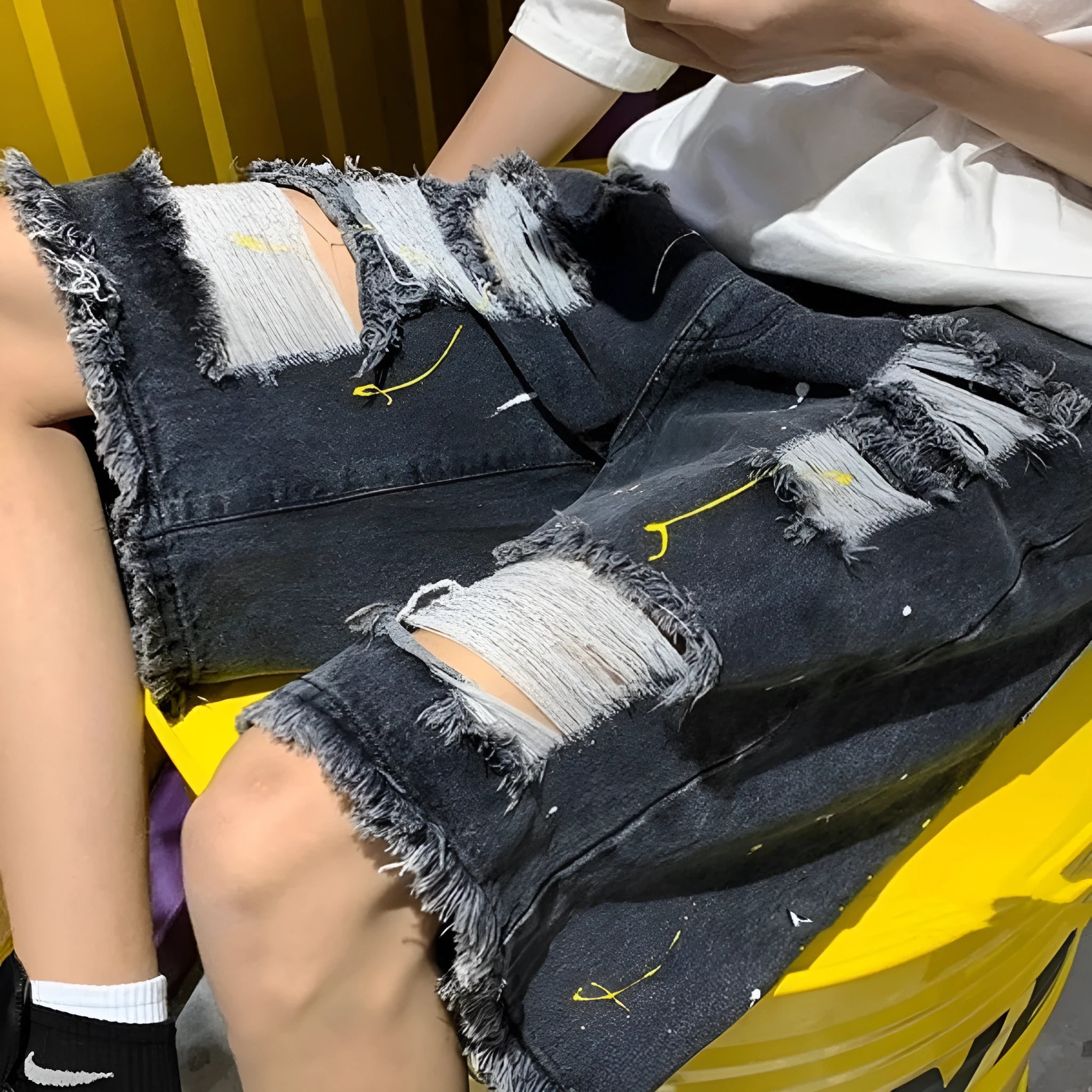 Men's loose-fit denim shorts with water-washed finish and hole detailing in light blue.
