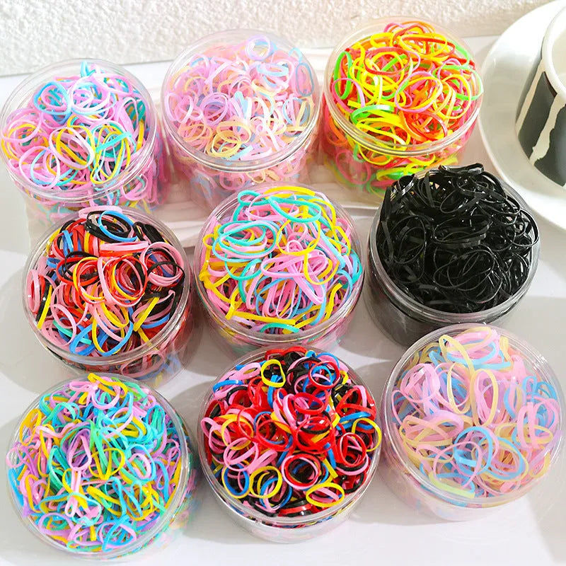 Assortment of colourful thin TPU baby hair ties in a clear reusable plastic container.