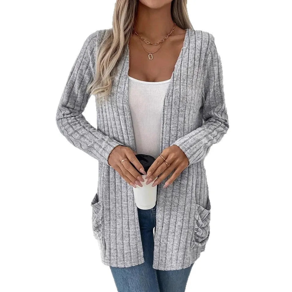 A grey loose fit long sleeve cardigan with pockets hanging on a hanger.