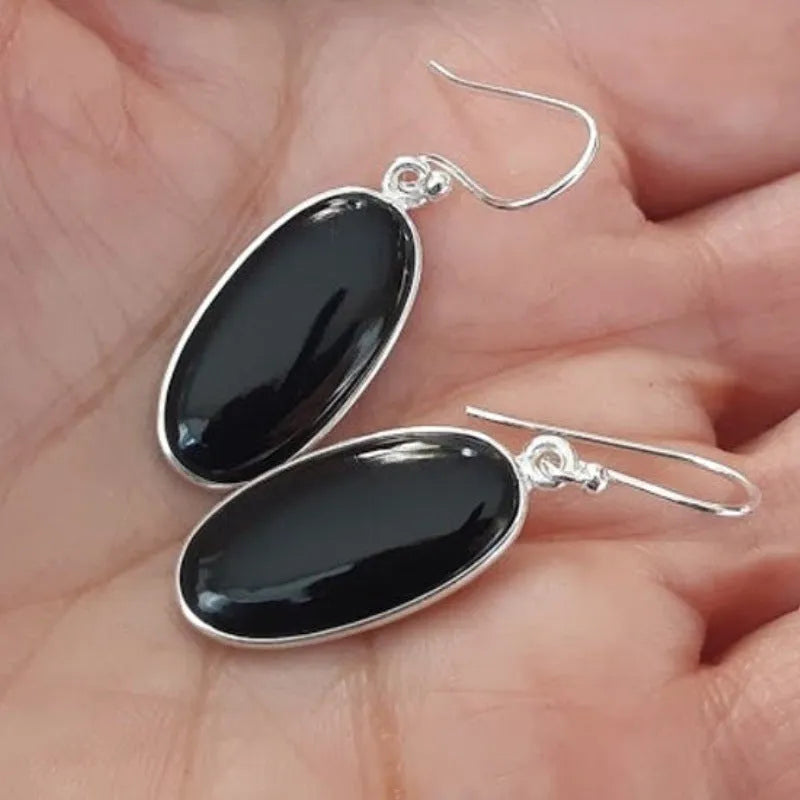 Pair of women's earrings with oval black agate pendant on silver electroplated alloy geometric setting.