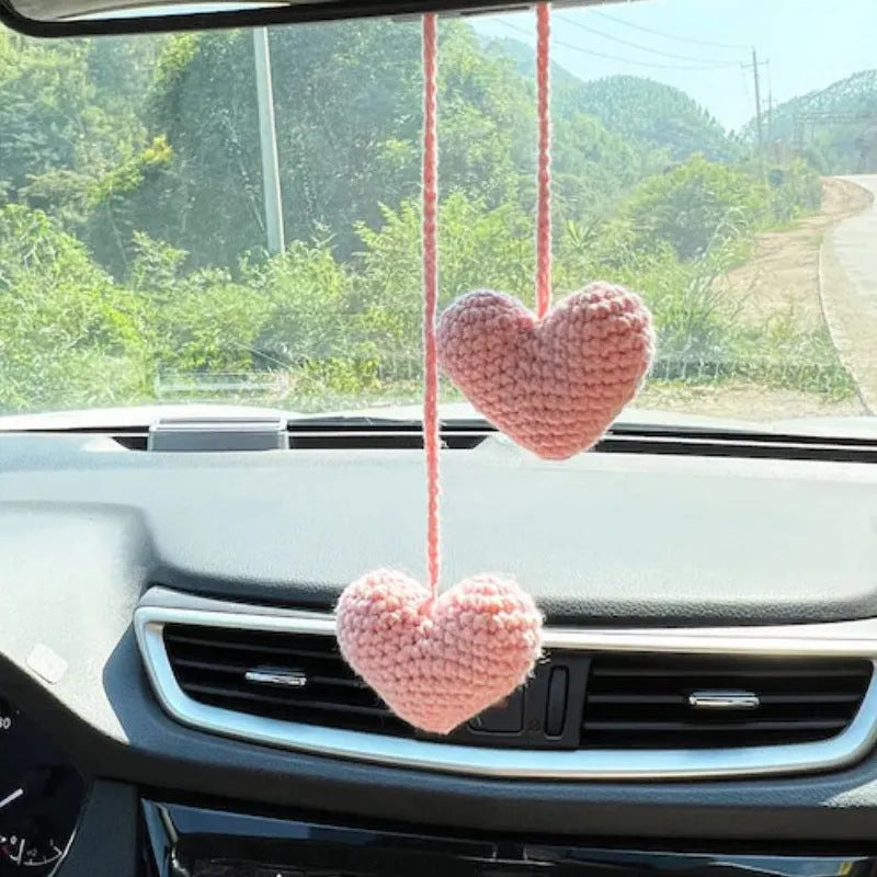 Green and white knitted wool car plant decoration with white hanging rope.