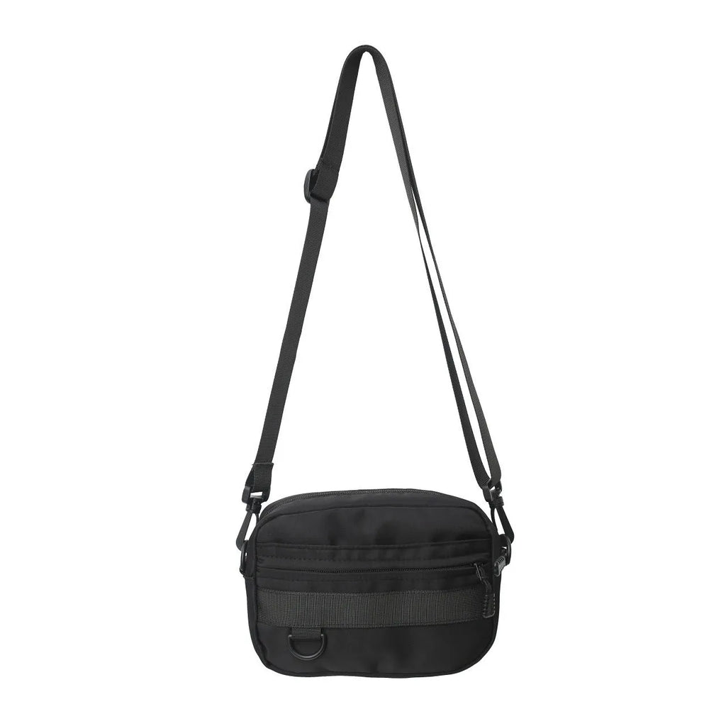 Men's solid colour nylon messenger bag with crossbody strap, shown in street style.
