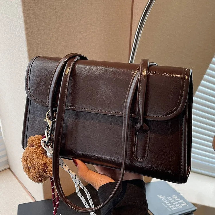 Women's brown PU leather square shoulder bag with pendant accessory showing interior zipper compartment