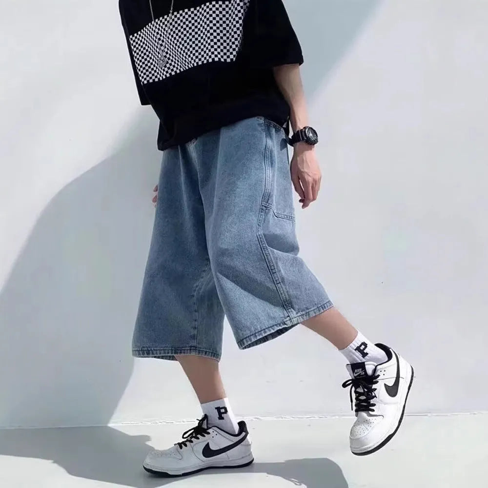 Blue washed denim shorts for men with high waist and cropped pirate-style legs on a plain background.