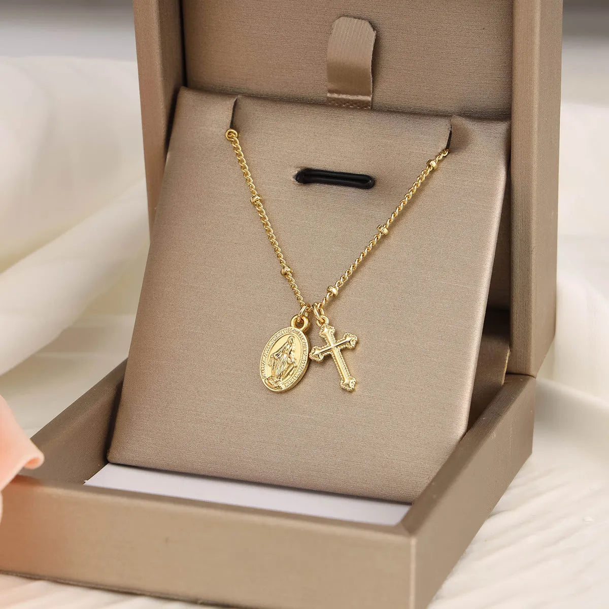Gold geometric cross and Virgin Mary pendant necklace on display