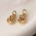 A pair of gold-toned geometric drop earrings with an irregular shape, made from copper.