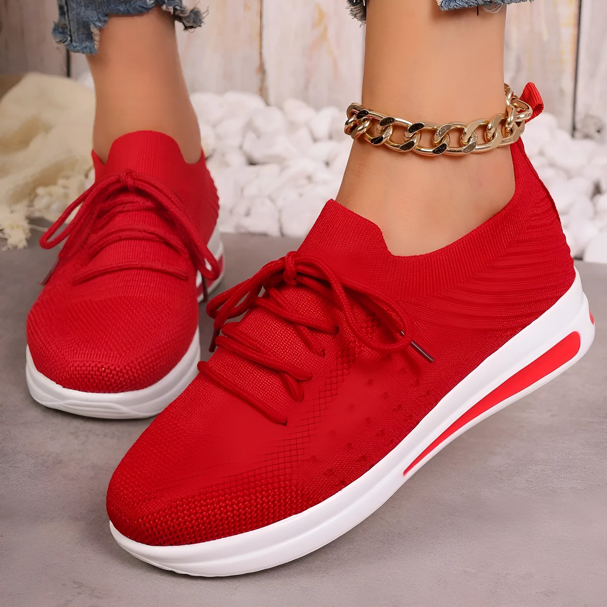 Women's low-top red fly-knit sneakers with round toe and lace-up front on a white background.