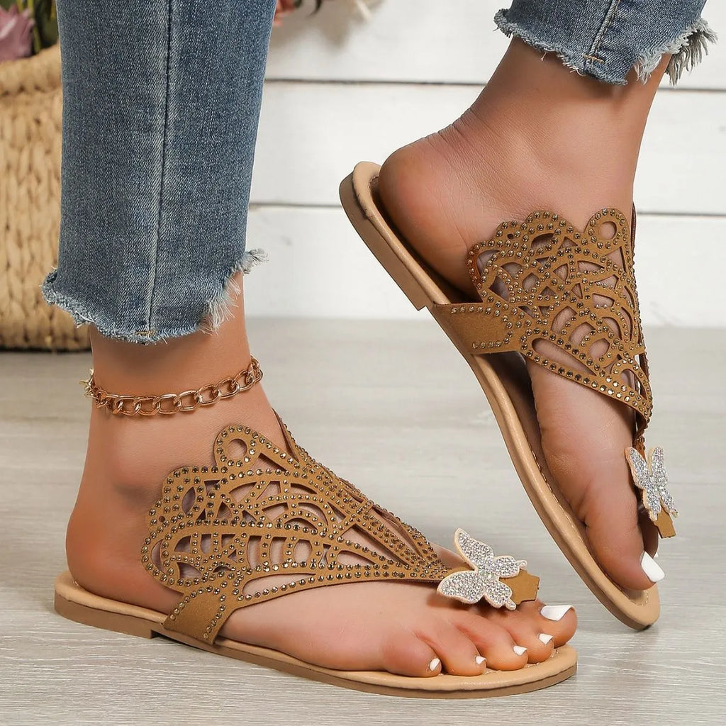 Women's black slip-on sandals with rhinestone flip-toe design and hollow detailing on the upper.