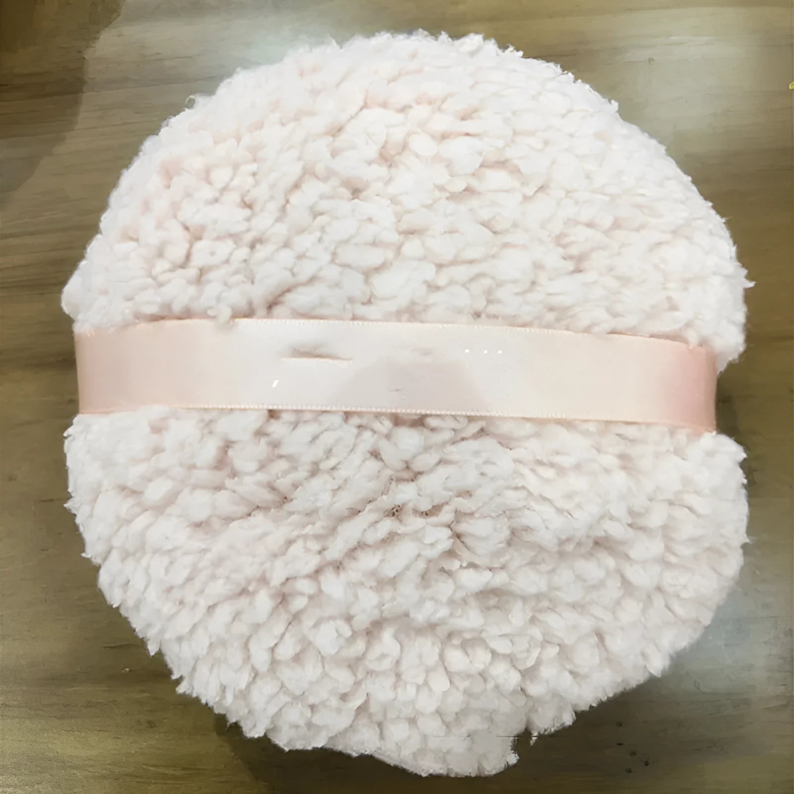 Oversized white plush powder puff measuring 150mm by 75mm for makeup application