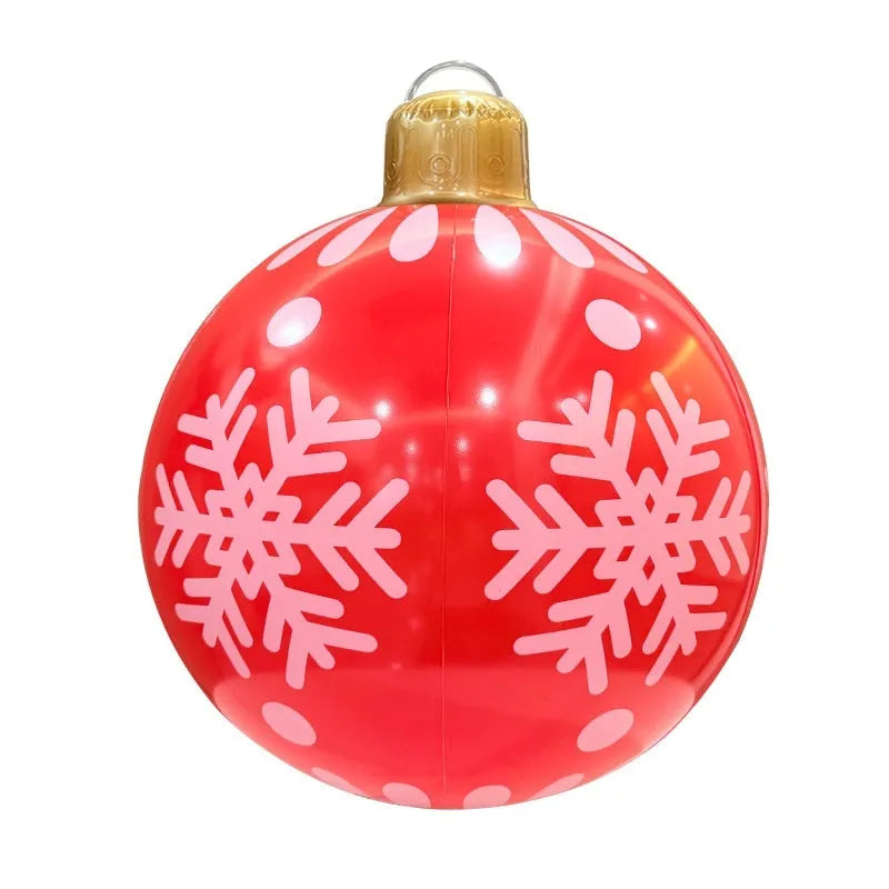 Large red and white inflatable Christmas ball with snowflake design in garden setting