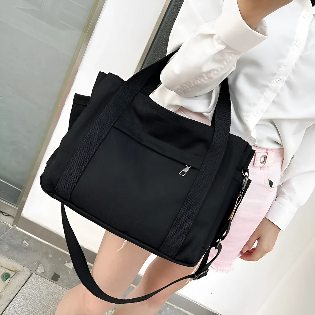 Large horizontal square canvas tote bag with cross-body strap, shown in army green colour with visible sewing lines.