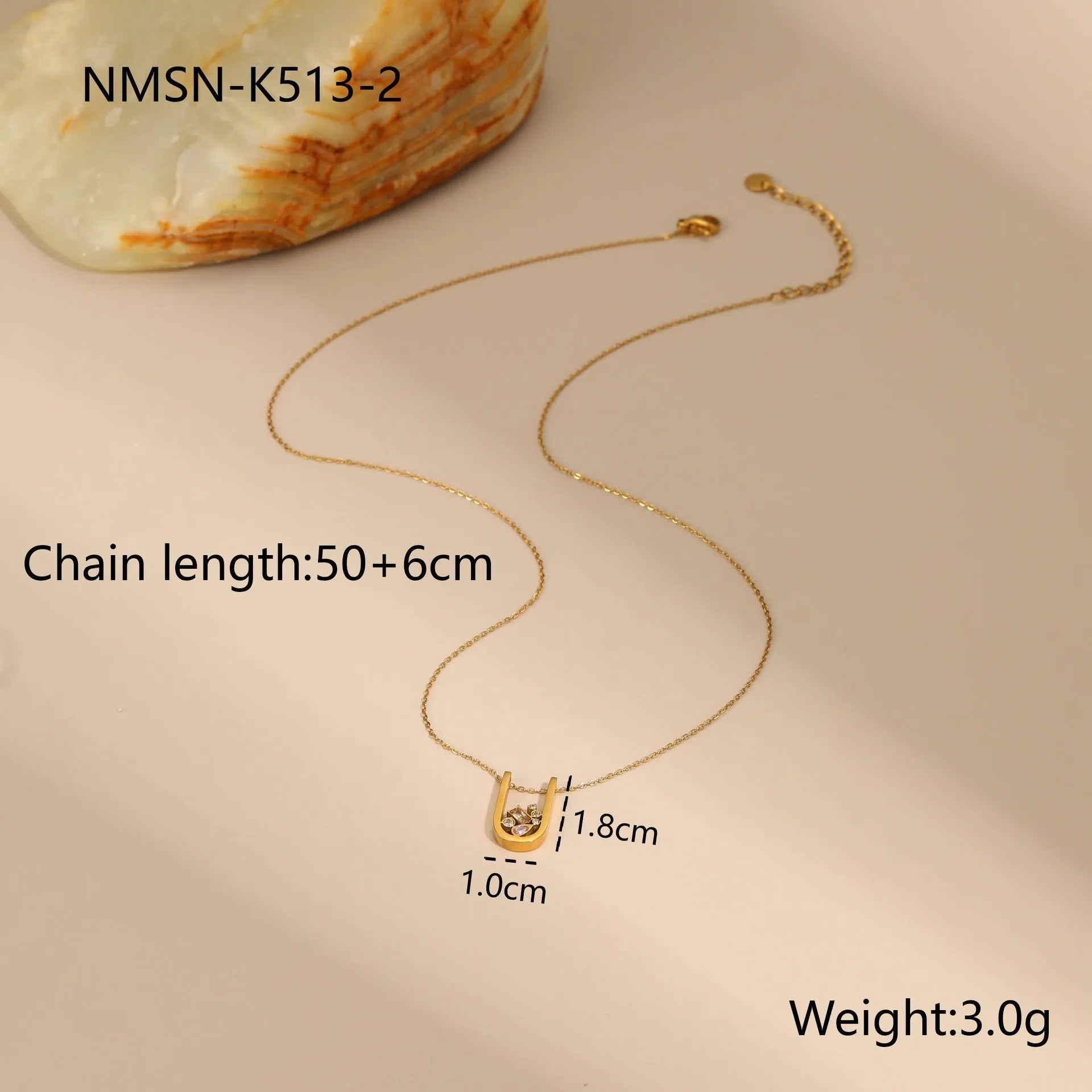 Geometric gold-plated necklace, ring, and earrings set with an adjustable chain on a grey background.