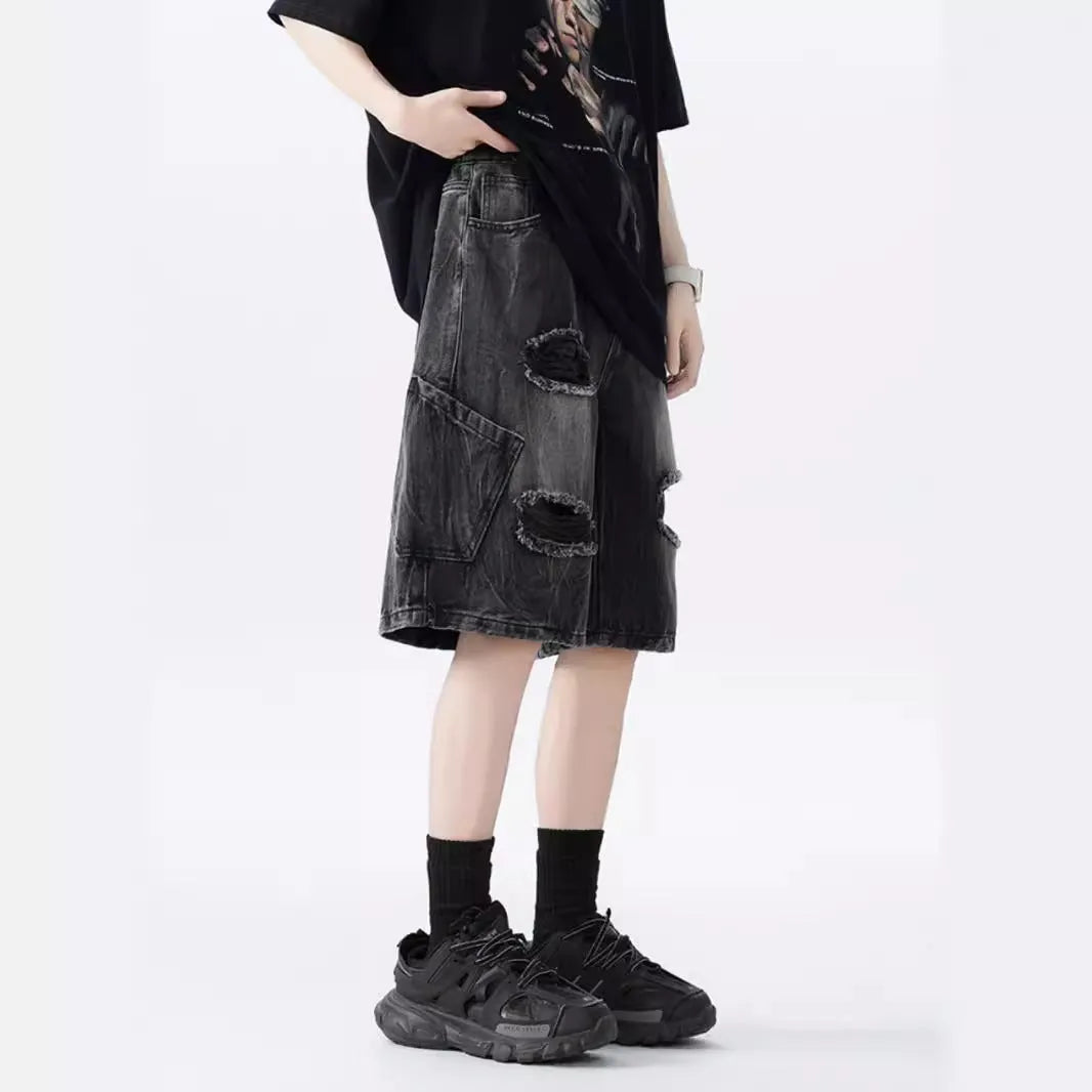 Man's loose-fit ripped denim shorts in washed black showing distressed details and retro styling