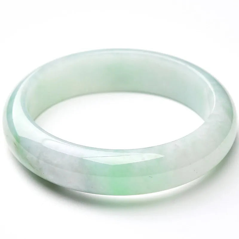 Light green polished jade bracelet in a natural style on a wrist.